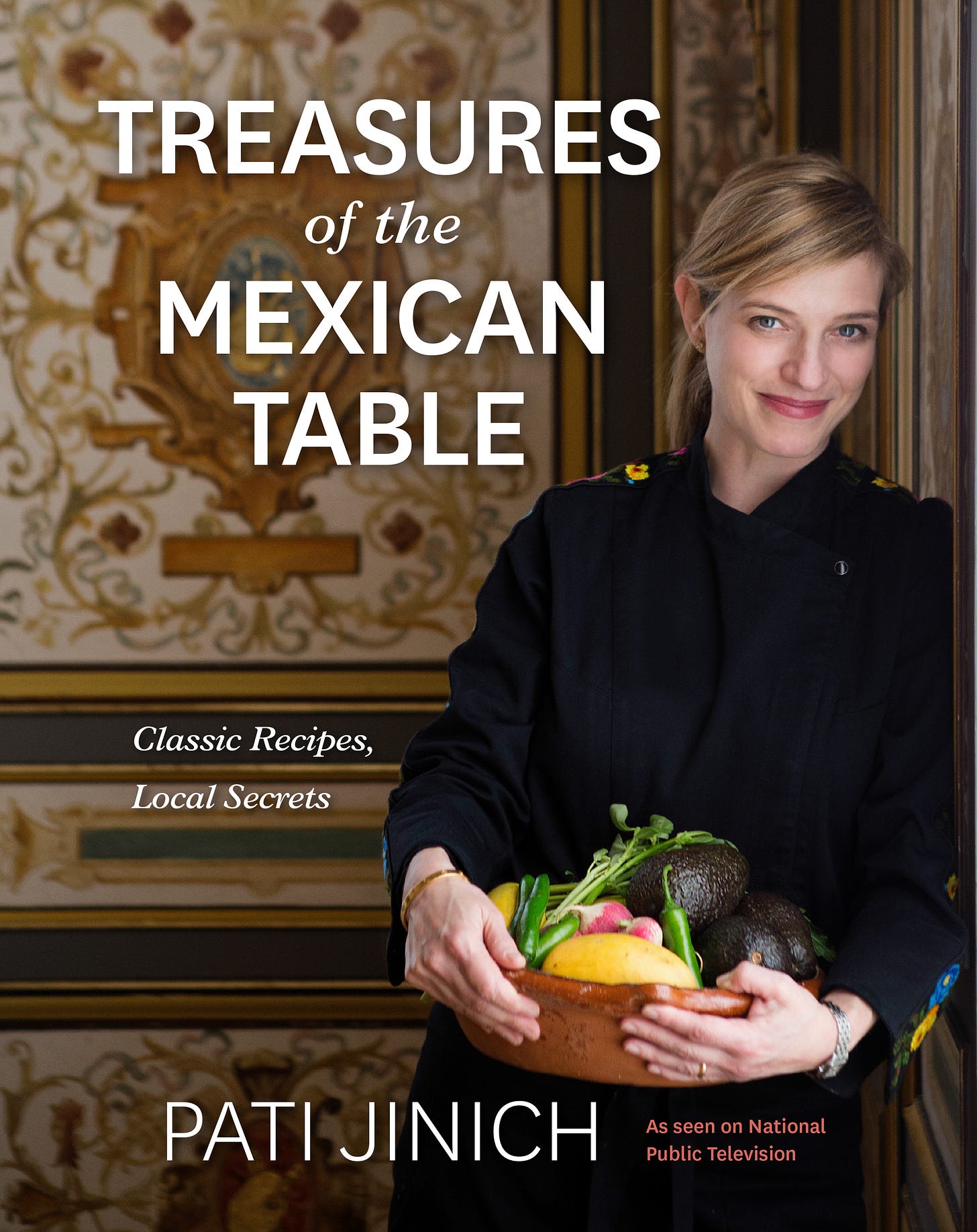Pati Jinich with a bowl of fresh produce in her arms on the cover of her cookbook, Treasures of the Mexican Table