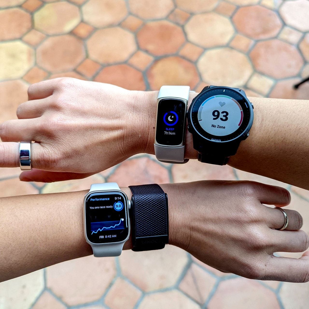 Two wrists wearing all of the modern wearable tech