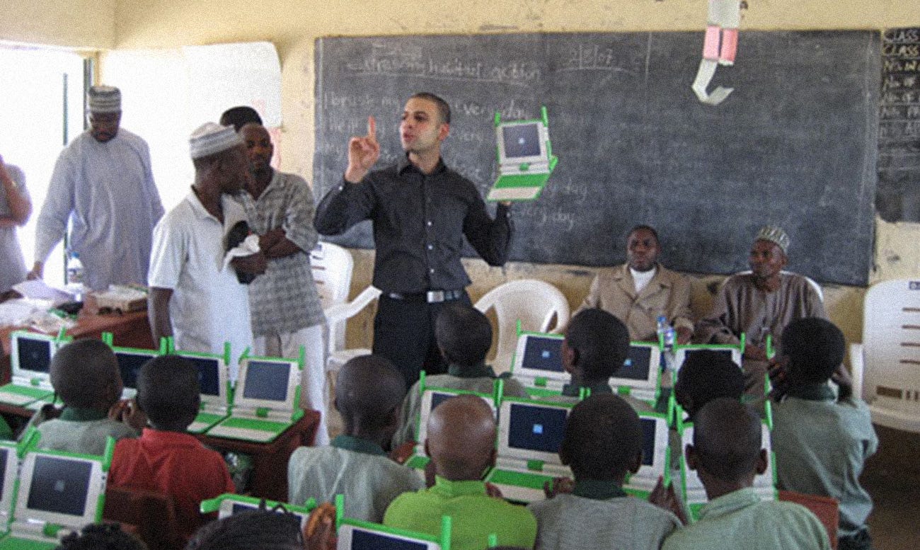 Photo of emerging market classroom where all the students have an OLPC. There is a western instructor teaching how to use the device.