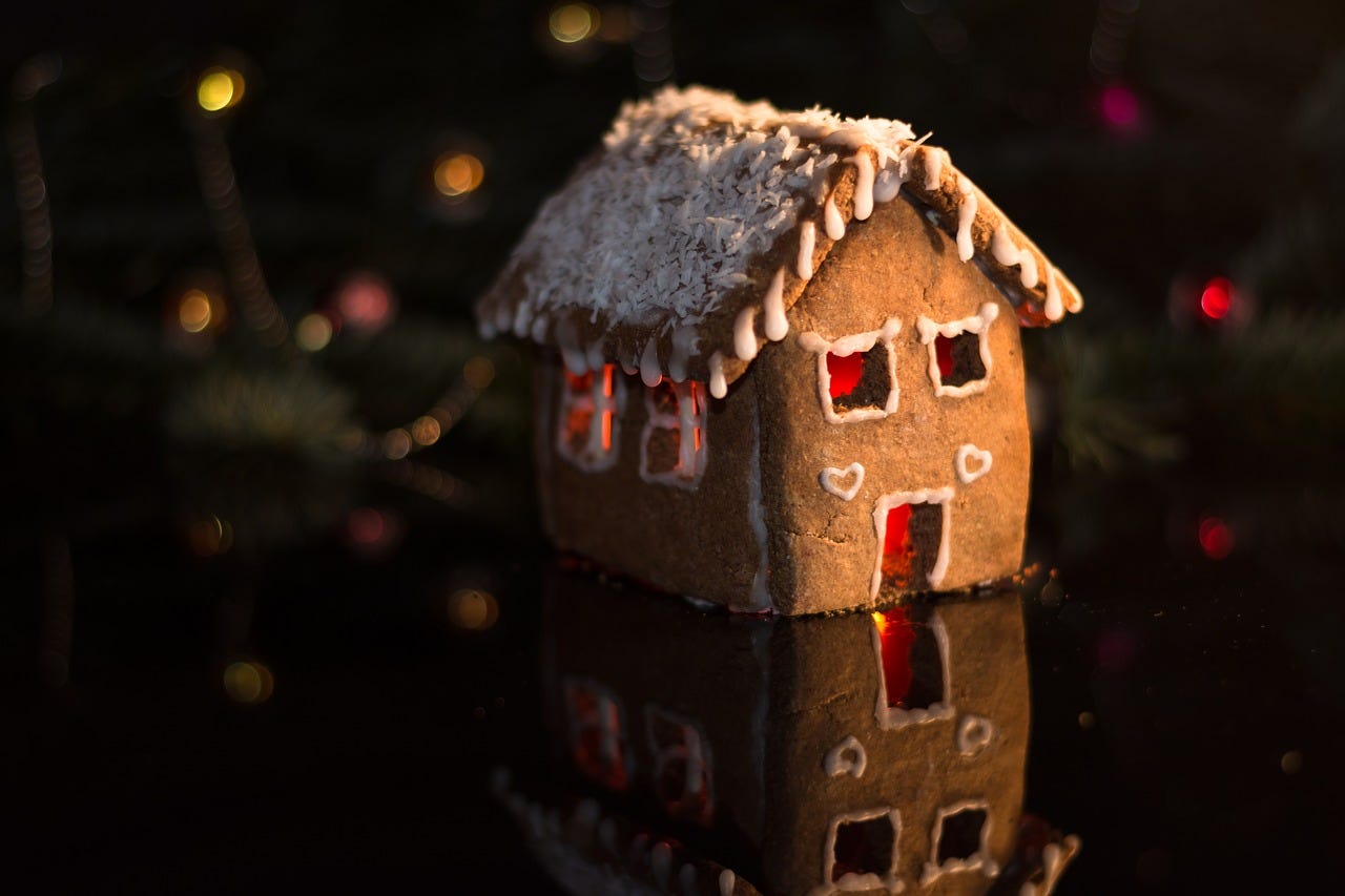 Homemade gingerbread cottage in front of a Christmas tree.