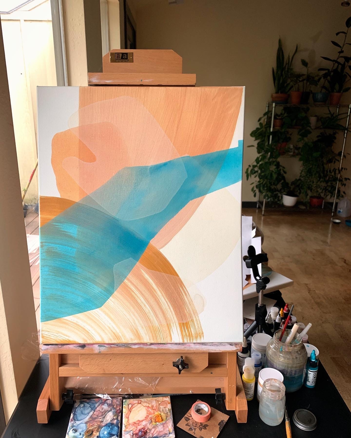 abstract paintings in process with light peach and teal colors
