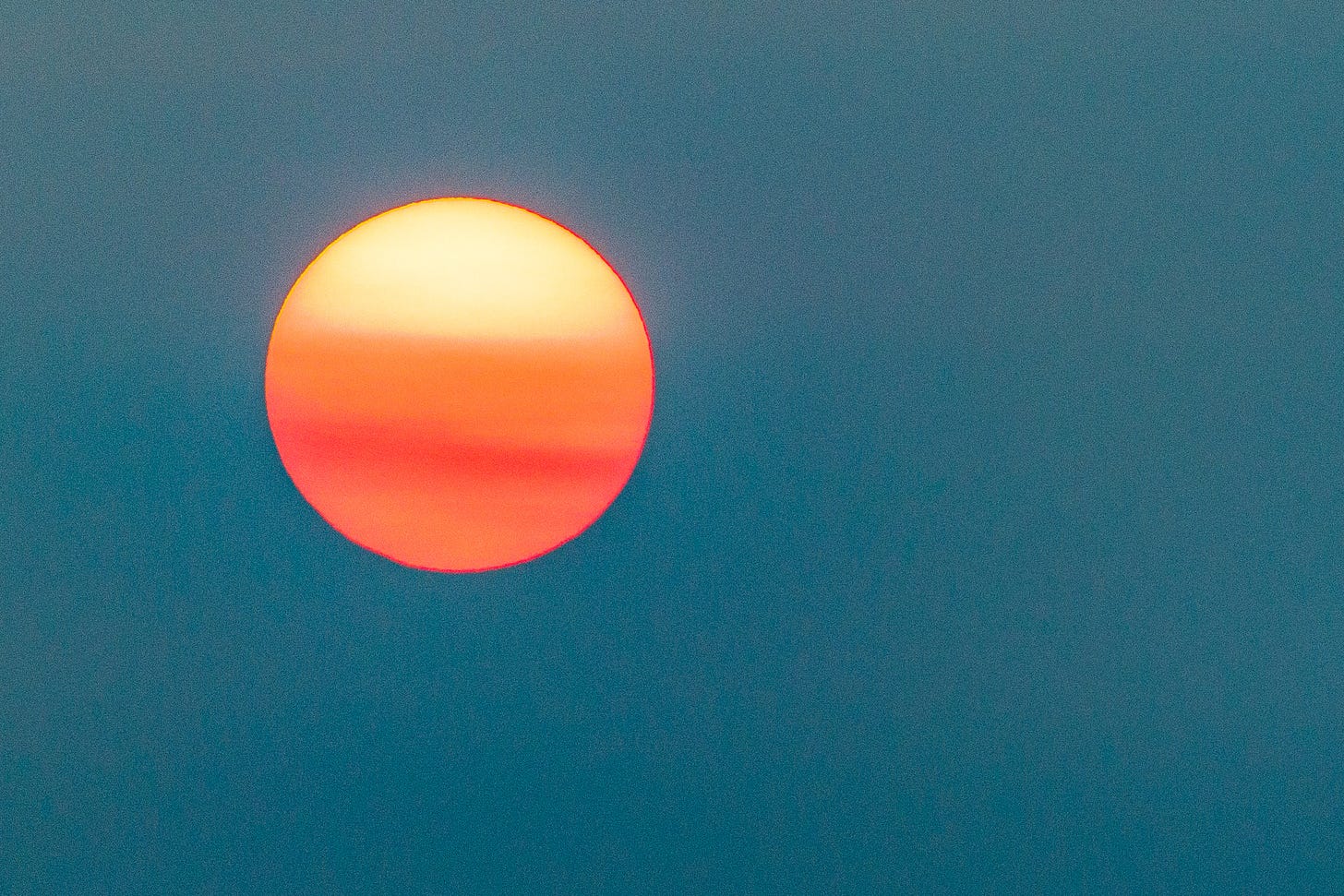 Hazy sun hangs orange against a teal sky