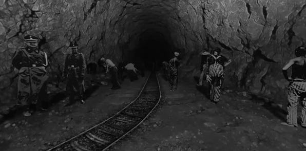 prisoners and guards in tunnel with narrow grade train tracks.
