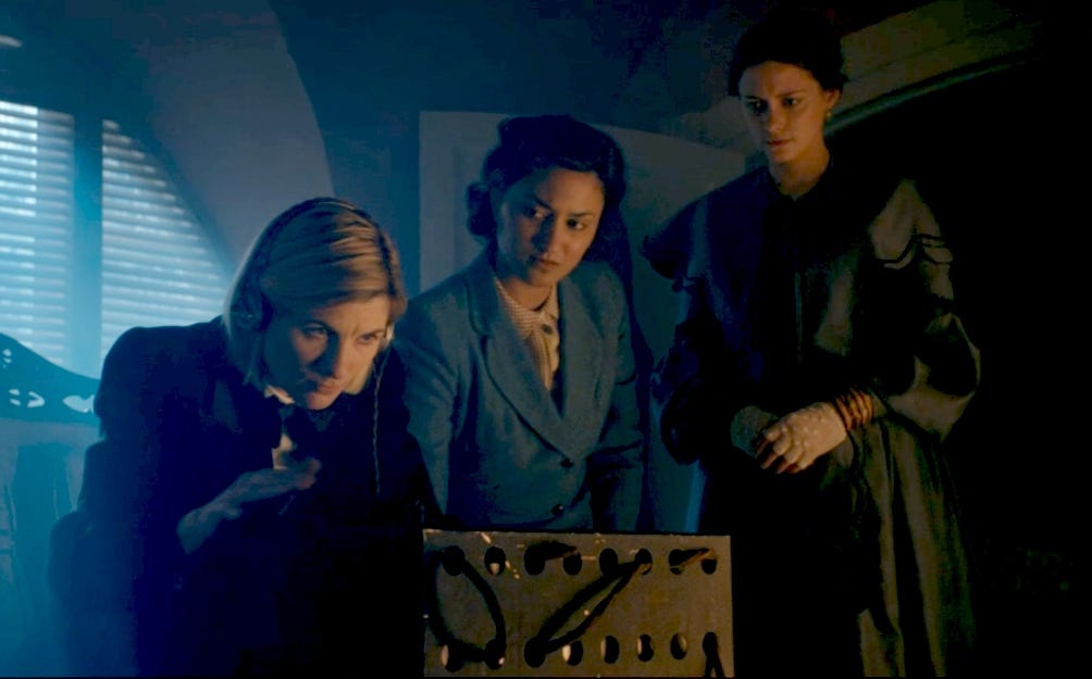 This image shows, from left to right, the Thirteenth Doctor (played by Jodie Whittaker), Noor Inayat Khan (played by Aurora Marion), & Ada Lovelace (played by Sylvie Briggs) working on a transmitter inside Noor's room in 1943 Paris, France.