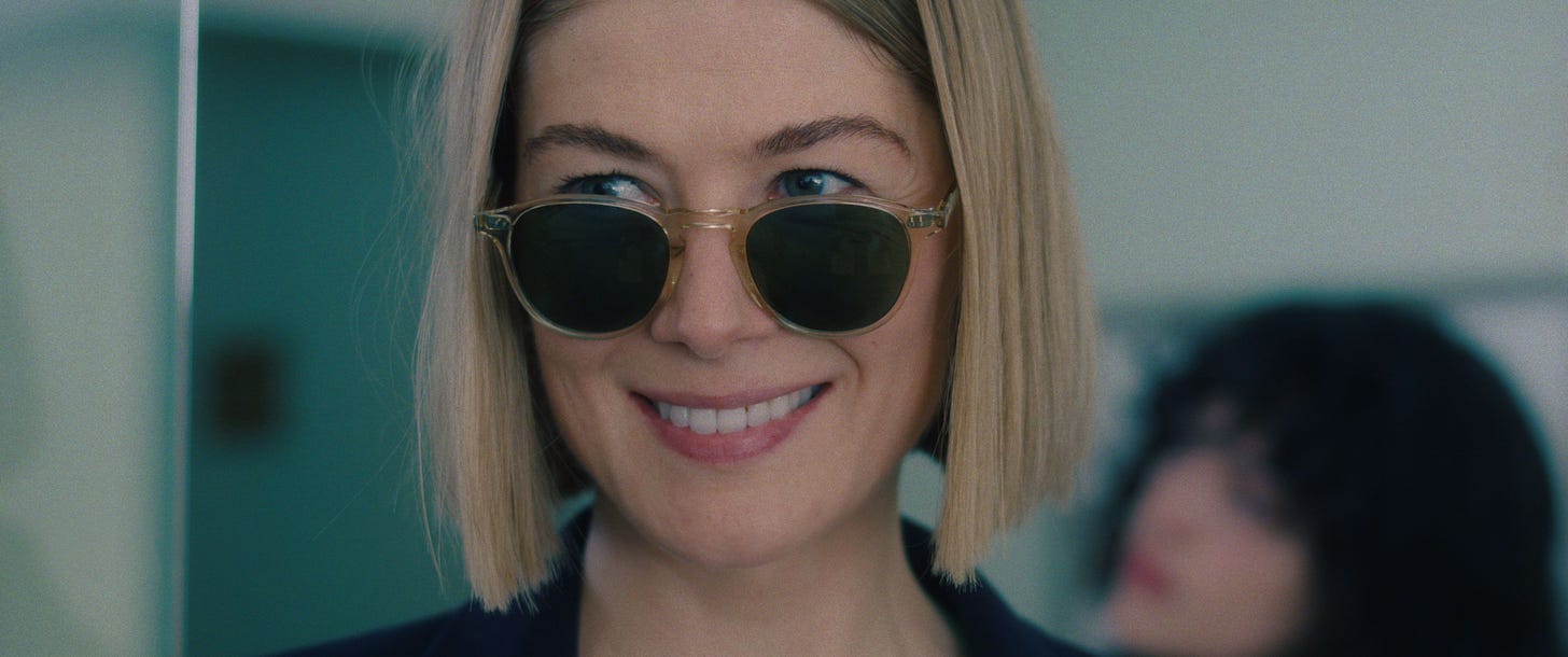 Shot of Rosamund Pike as Marla in I CARE A LOT looking over the top of her sunglasses and smiling