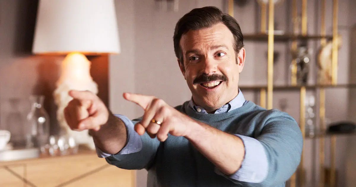 TV Character Tedd Lasso of Apple TV pointing at someone with a happy expression