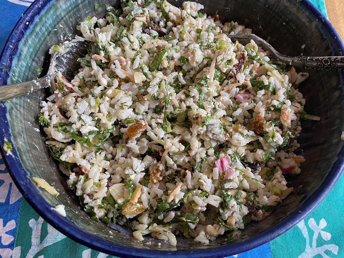 A big blue ceramic bowl full of rice salad, studded with silvered herbs and bright pink pickled shallots.