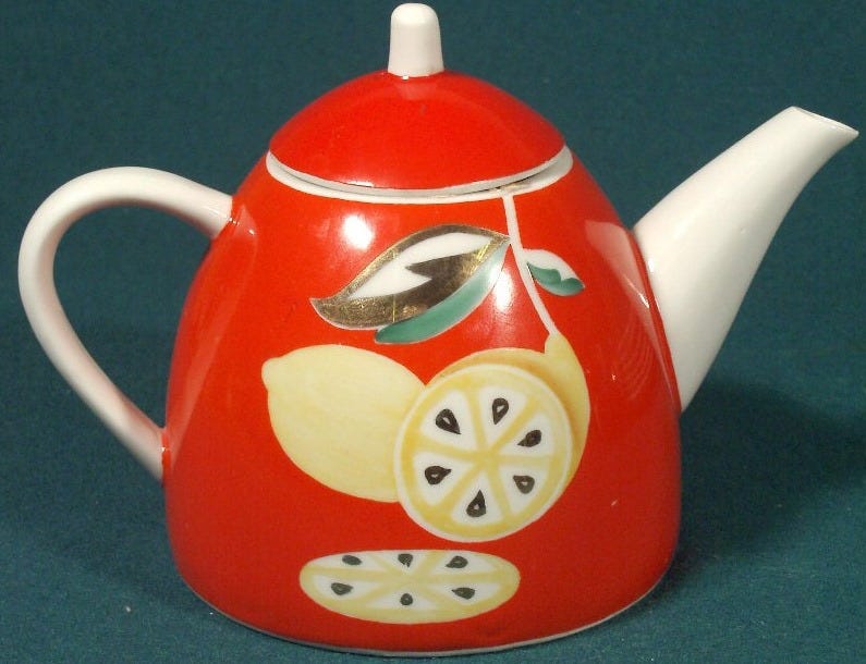 A Red teapot with a sliced lemon painted on it.