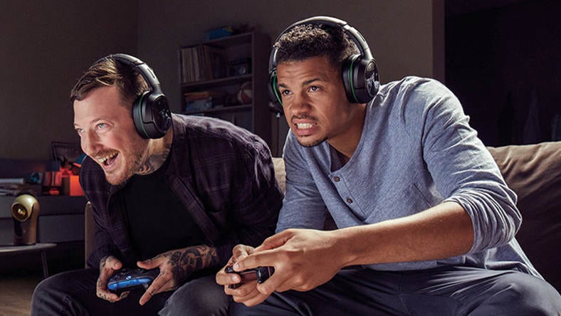 Two men wearing headsets and holding Xbox controllers