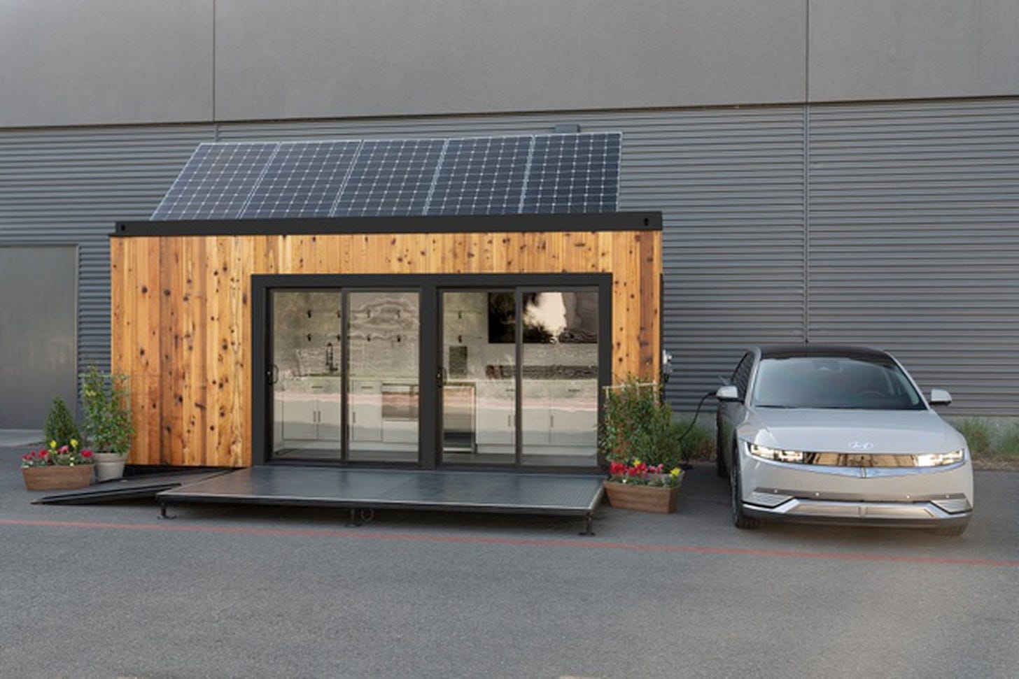 Hyundai electric vehicle next to a small home with solar panels