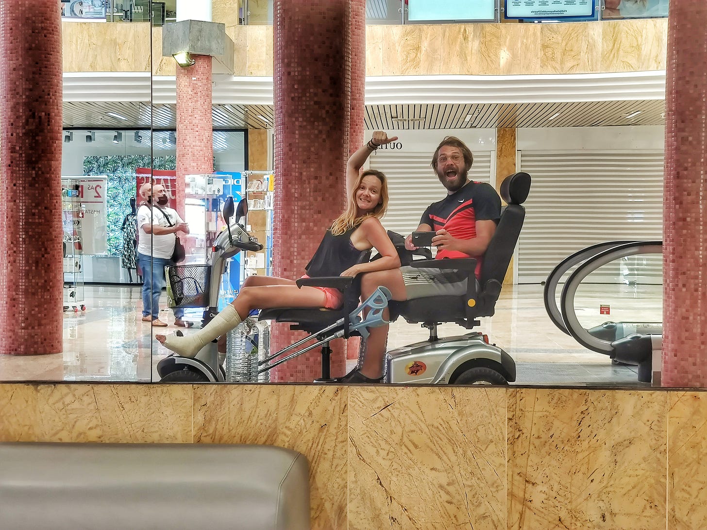 A hot couple riding an electrical scooter through a mall