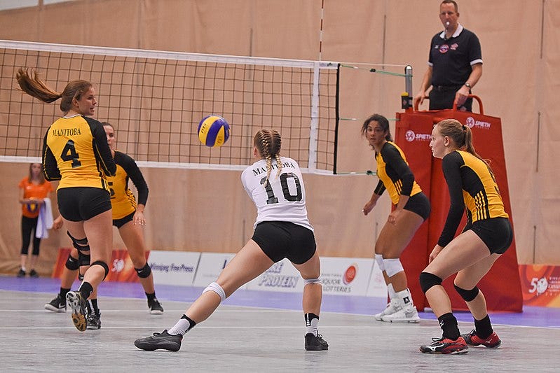 Libero receiving, surrounded by four players preparing for the pass.