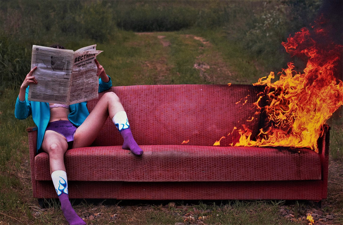 man sitting on couch in underwear reading paper couch is on fire