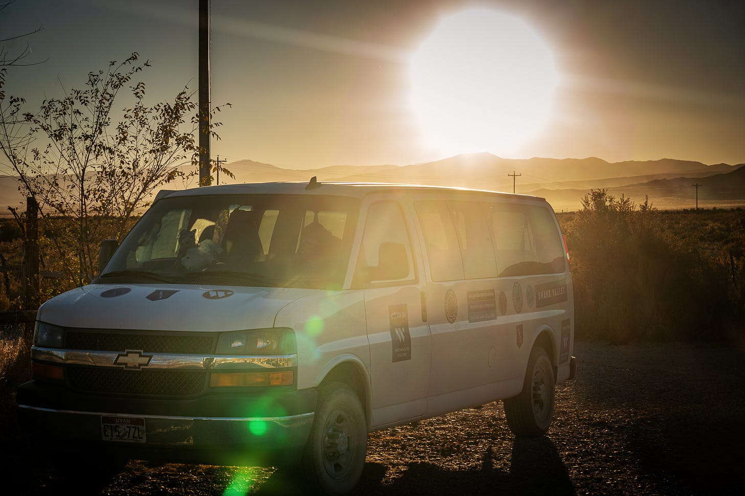 A van is parked on the side of the road in the desert at sunset