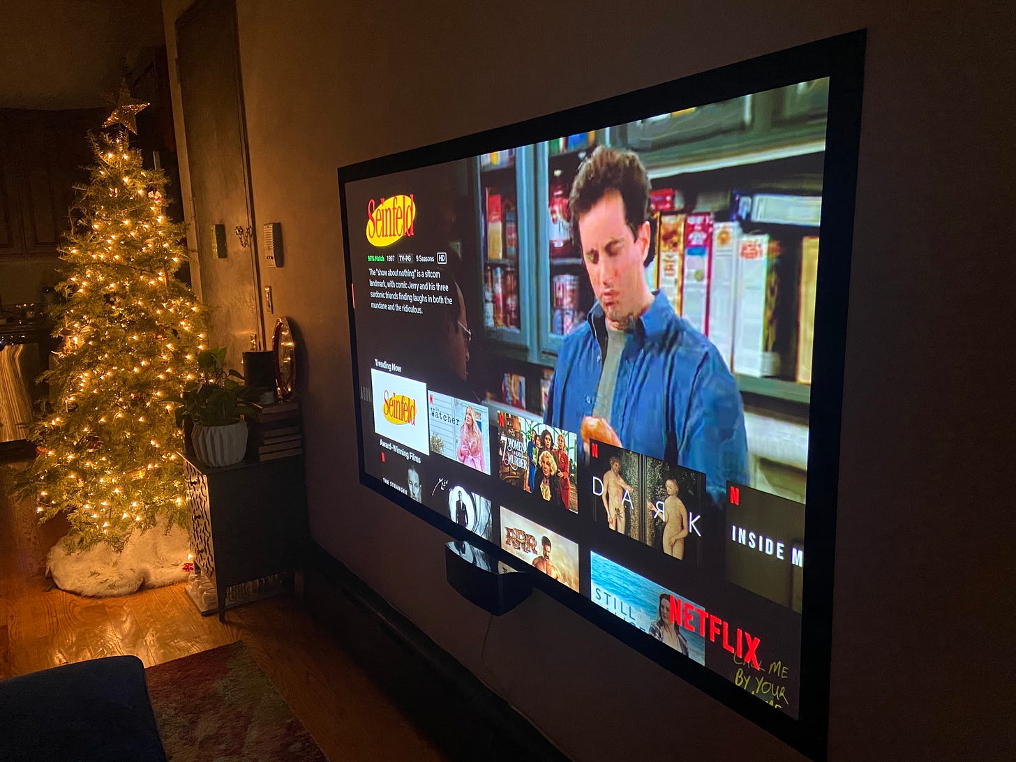 A Christmas tree lighting the new projector screen, which is displaying Seinfeld on the Netflix menu.
