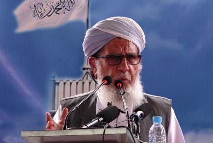 A person wearing a white turban and glasses speaking into a microphone

Description automatically generated with low confidence