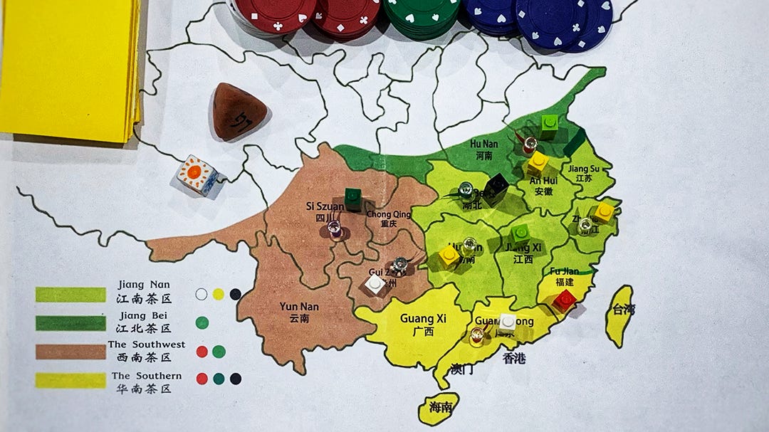 Paper map with regions of China highlighted and meeples placed throughout
