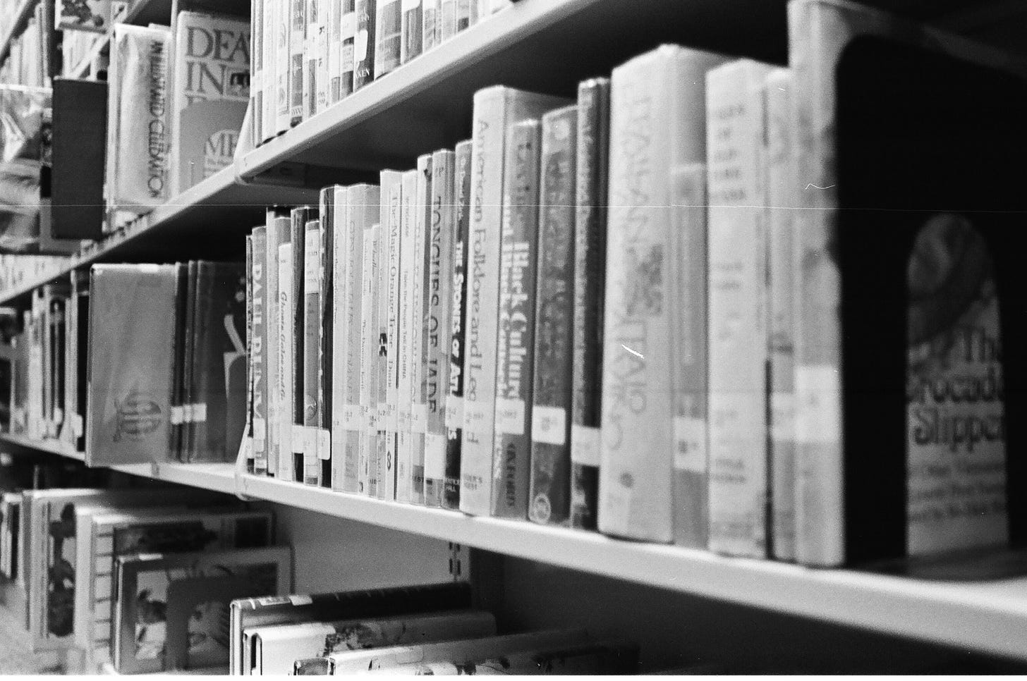 Row of library books in the stacks. Black and white. 
