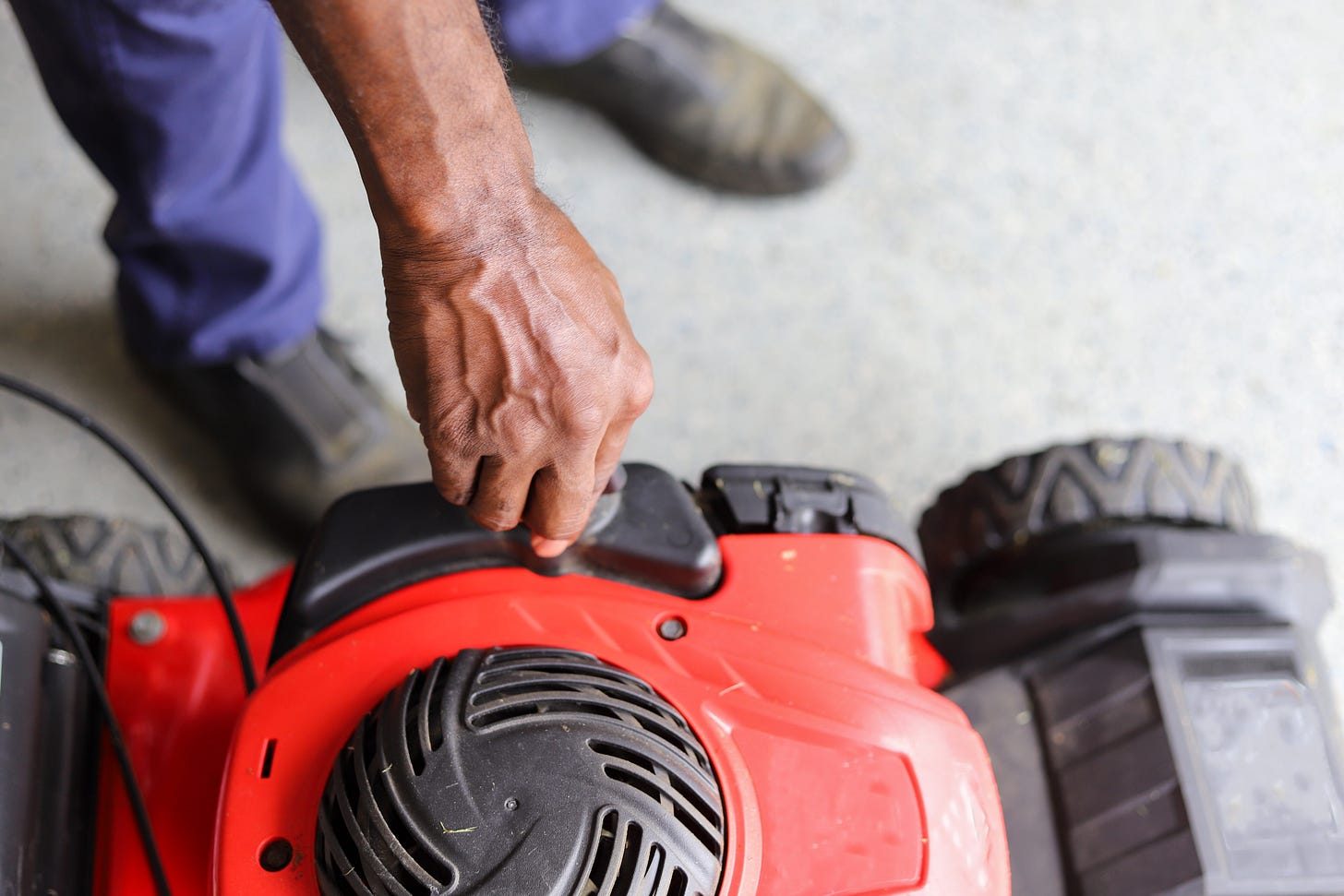 A hand turning the gas cap on a mower