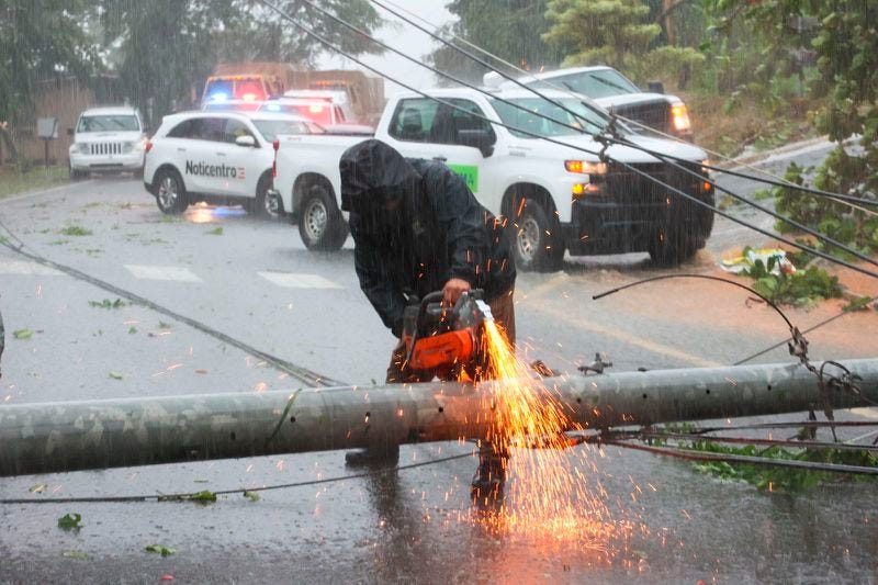 A worker cuts an electricity pole that was downed by Hurricane Fiona as it blocks a road in Cayey, Puerto Rico, Sunday, September 18, 2022. (AP Photo/Stephanie Rojas)
