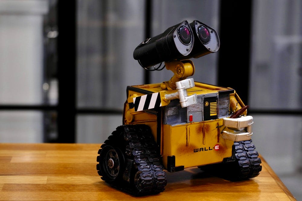 yellow and black Wall-E toy on brown wooden table