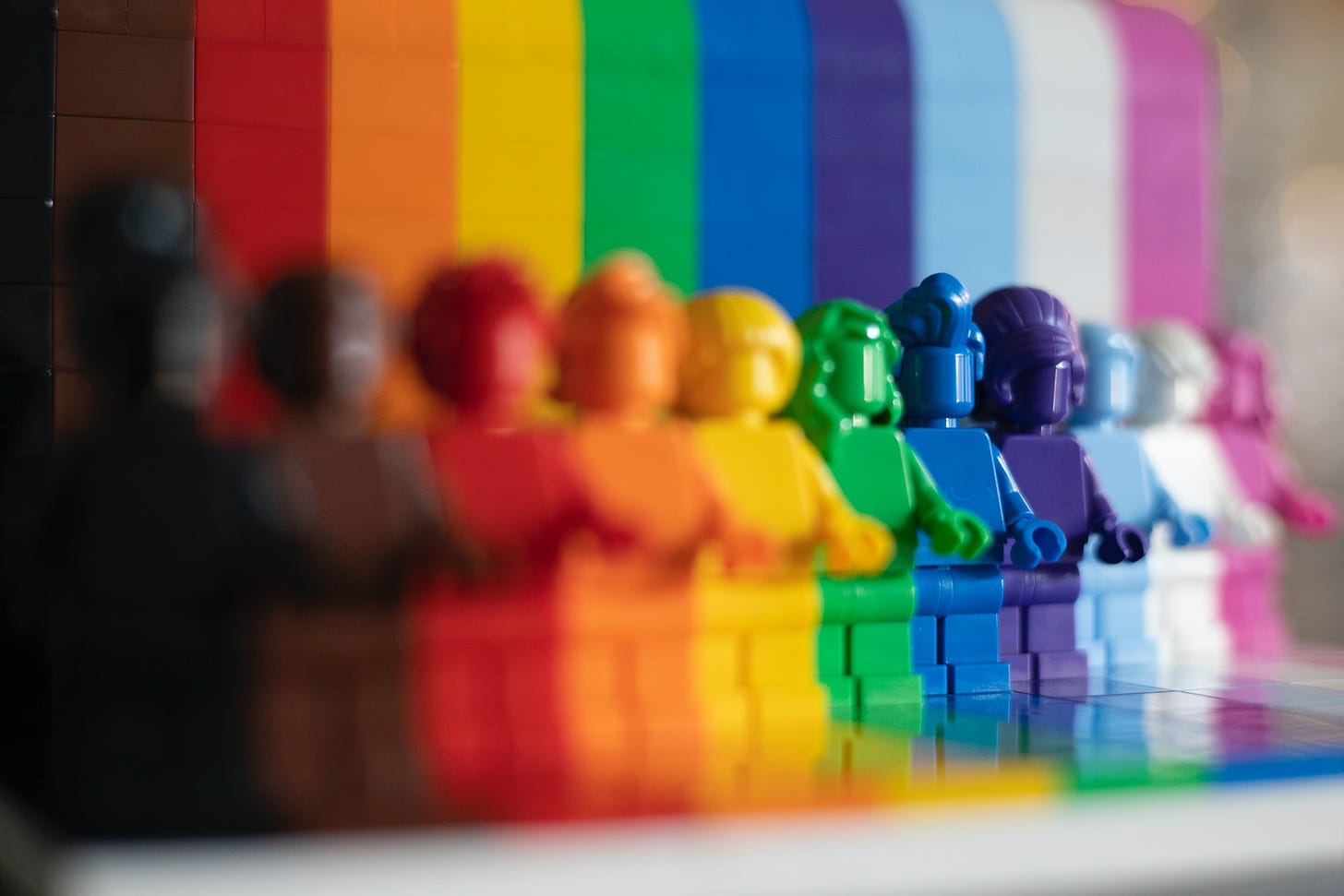Omini della Lego di tutti i colori, ciascuno davanti a un colore diverso che forma una bandiera arcobaleno.
