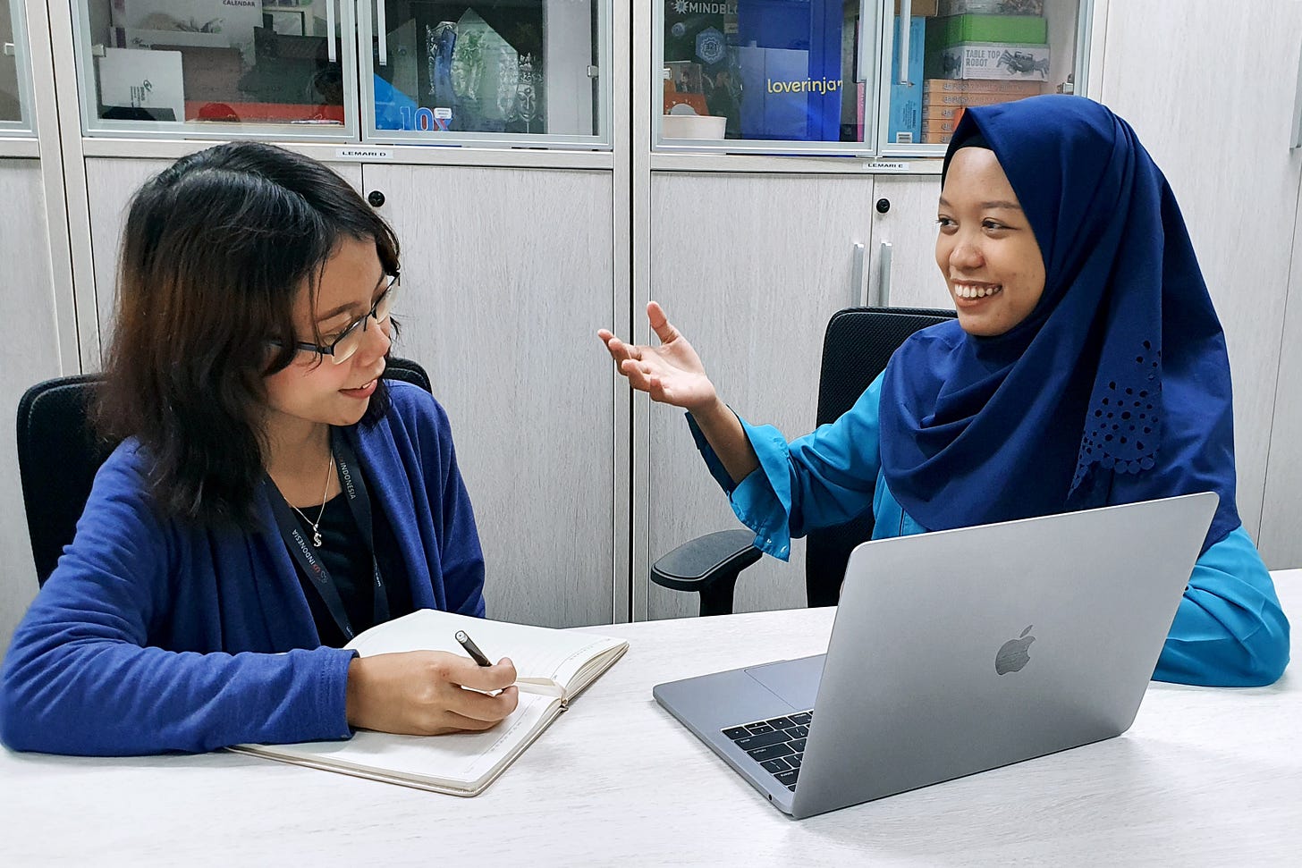 Two women talking in front of a computer