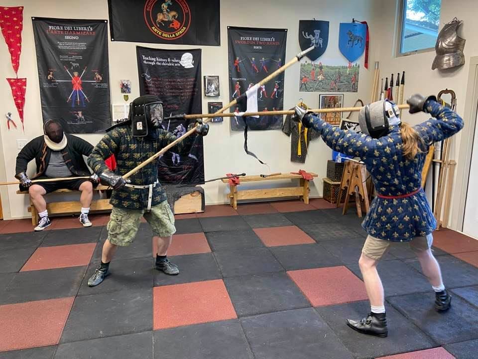 Two combatants spear in padded jackets and spears, dynamically showing the movement of the ancient martial art 
