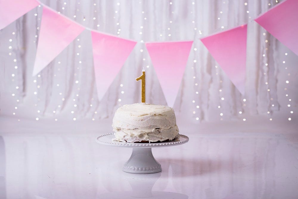 white and gold cake with pink umbrella