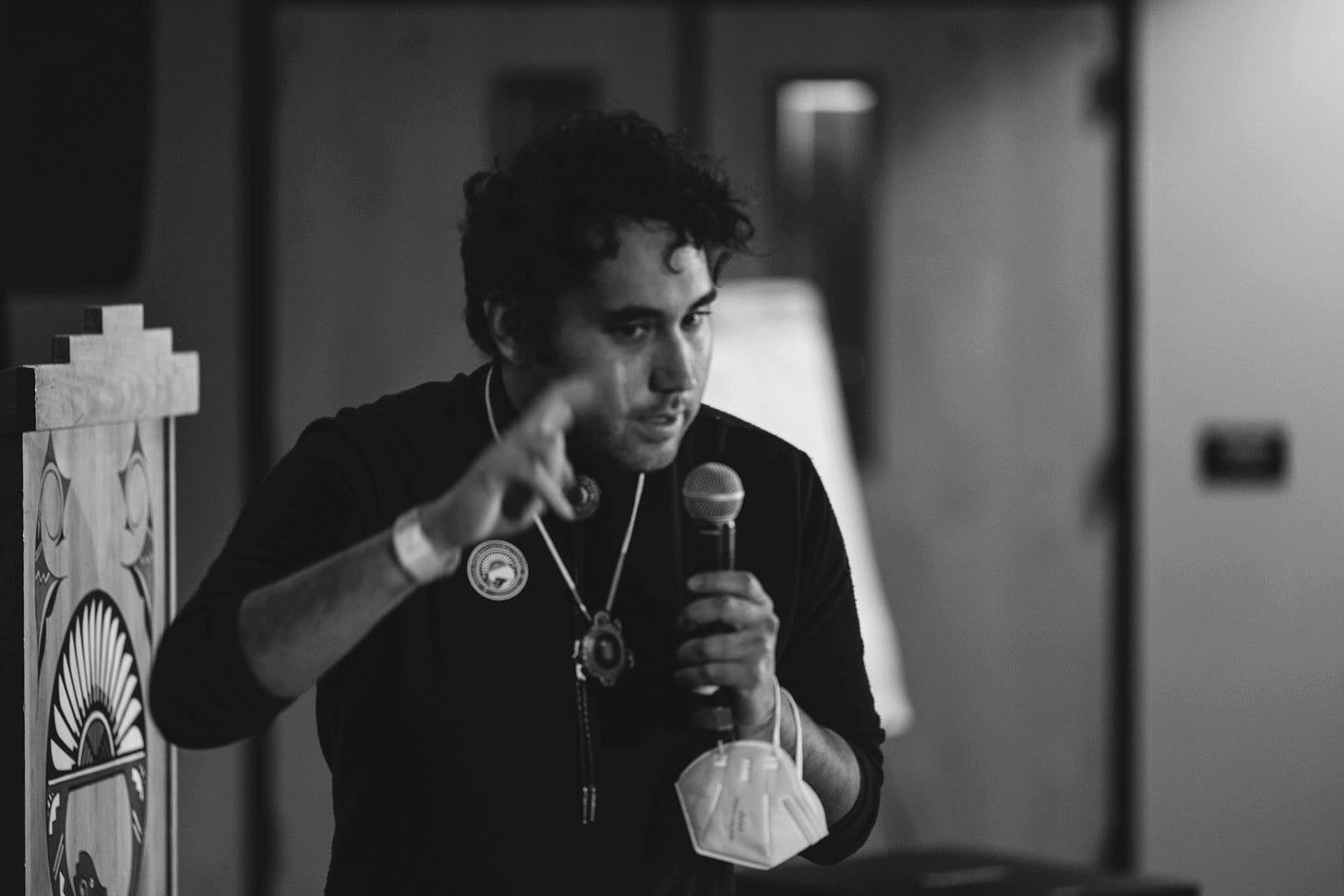 black and white photo of person speaking into microphone indoors