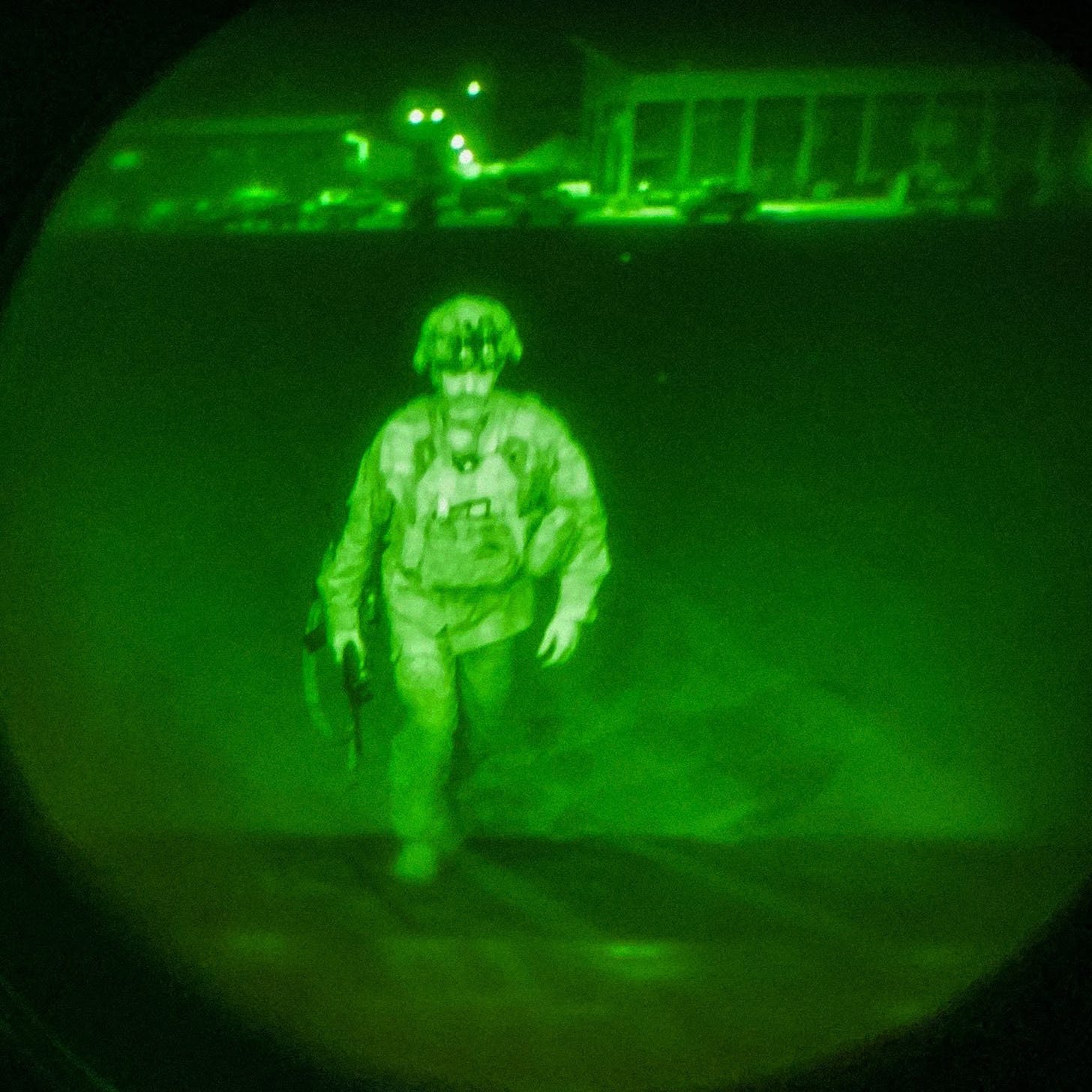 A man in full combat uniform boards a plane at night.
