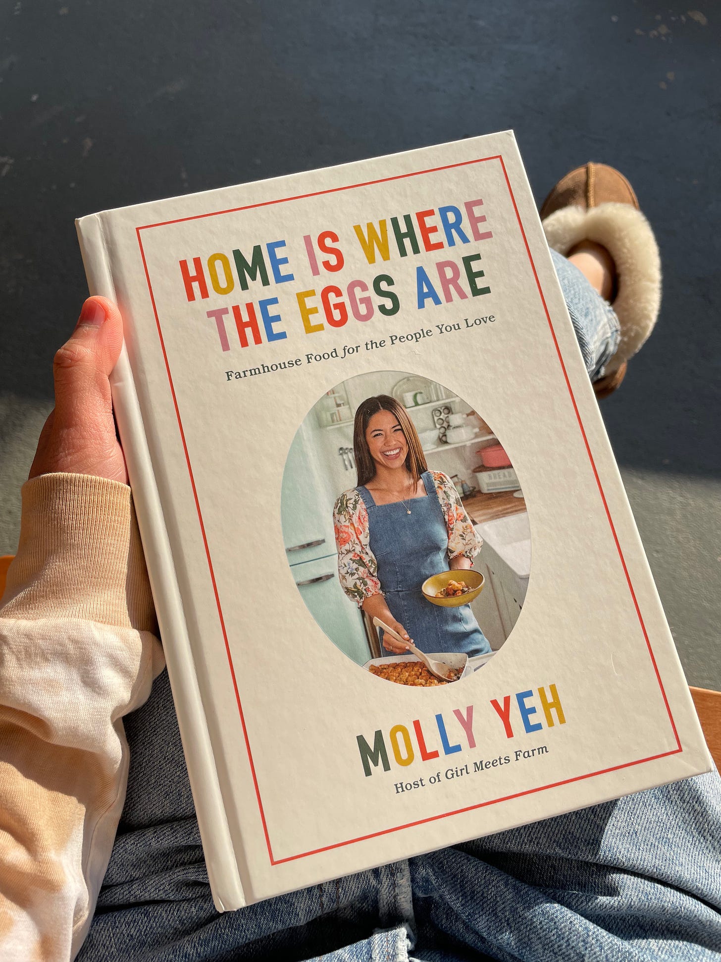Home is Where the Eggs are cookbook held in the sun. Molly Yeh is on the cover.