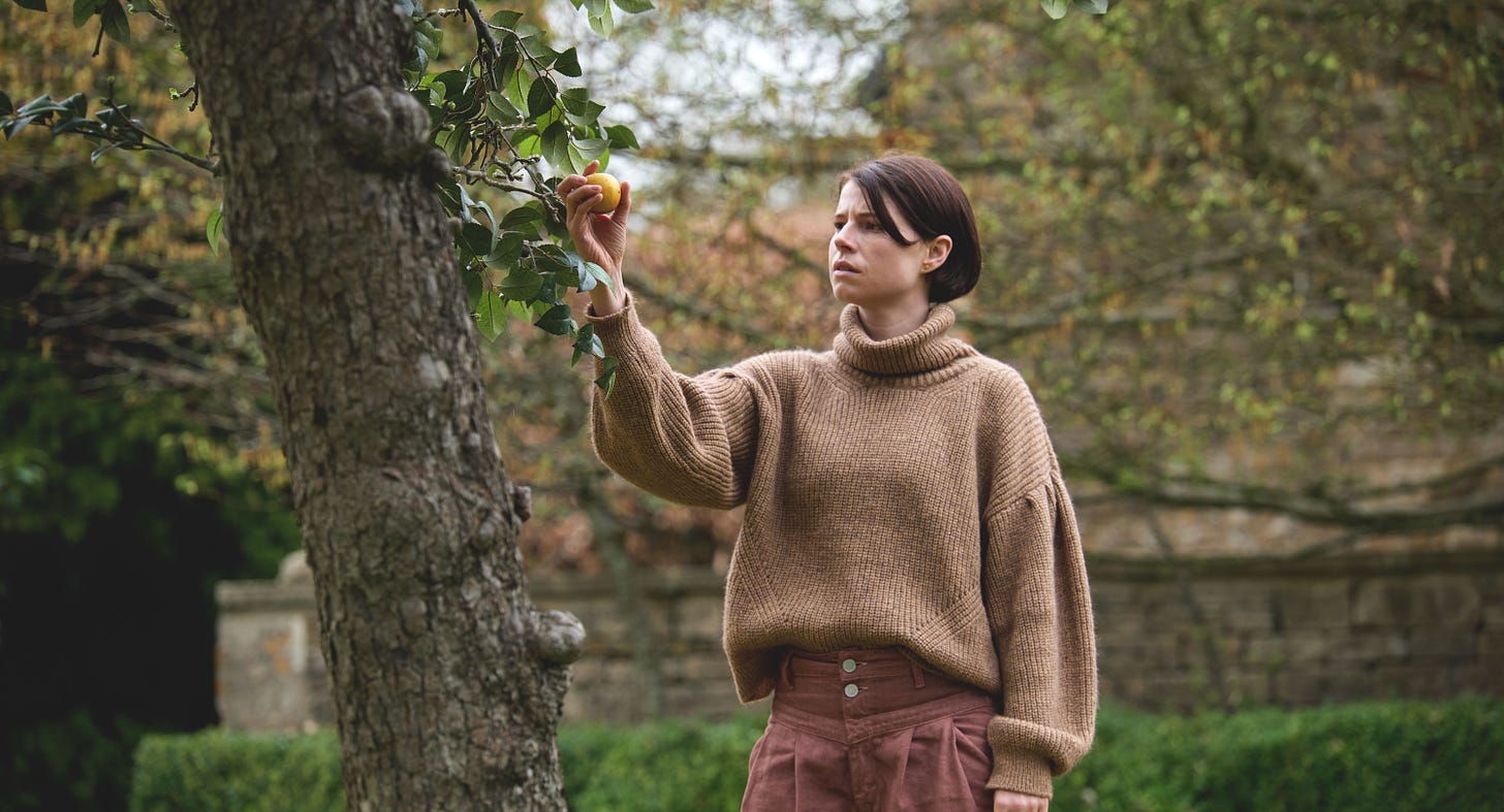 Jessie Buckley as Harper, reaching for an apple, in MEN.