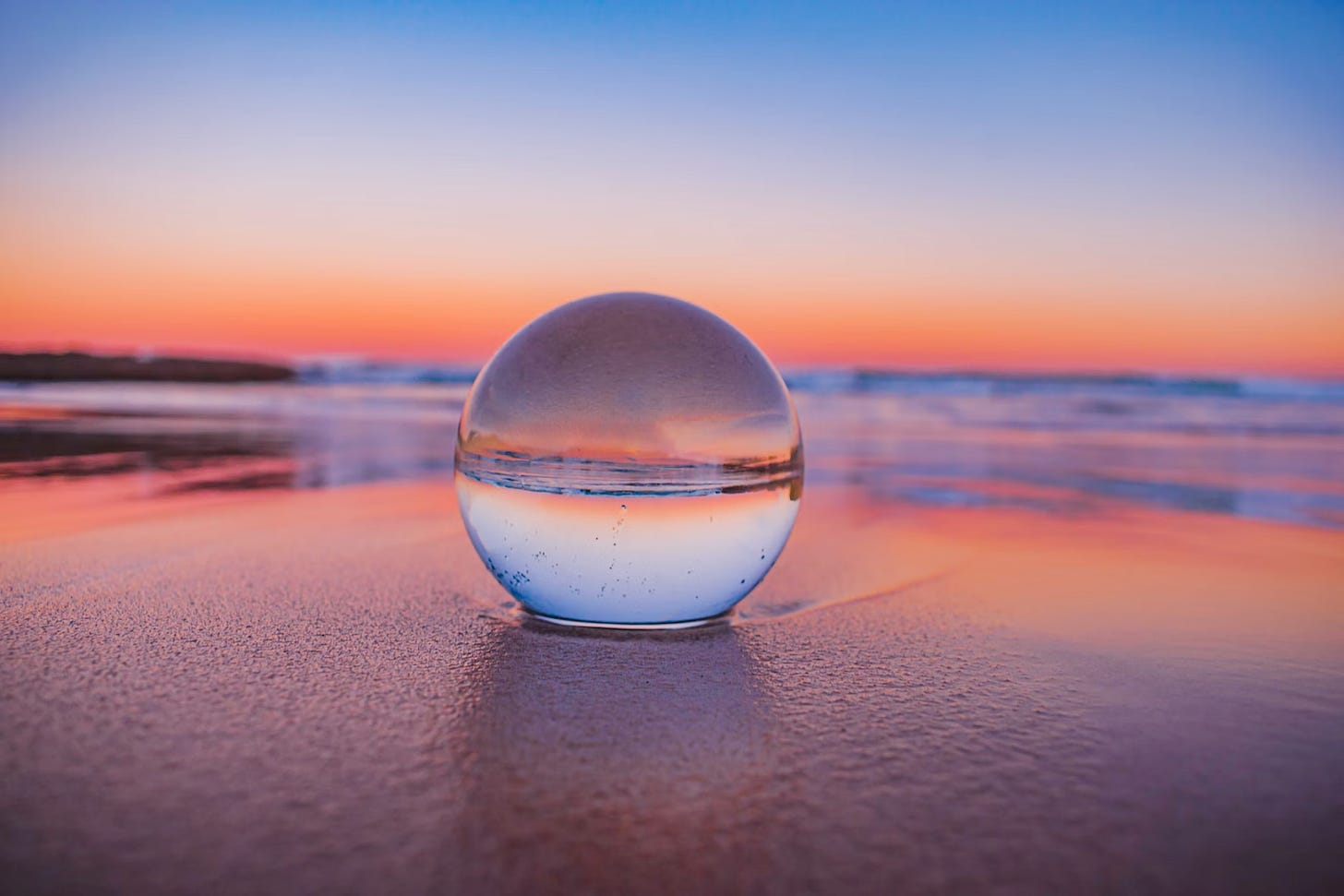 Low angle photo of a crystal ball on a beach at sunset