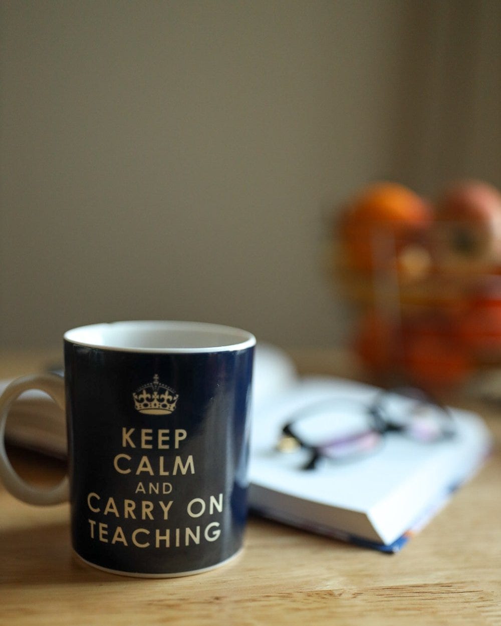 A blue and white mug and an open book with eye glasses resting on top