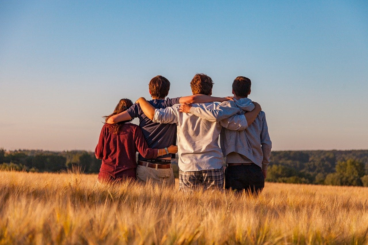 Four people in field with arms around each other in support.
