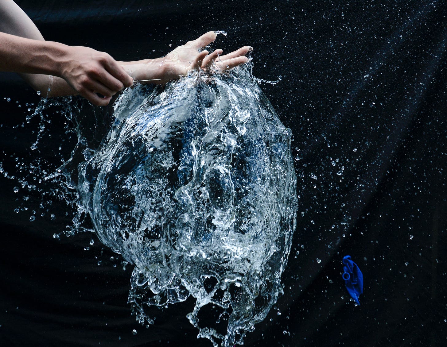 freeze frame photo of water balloon popped by a pin