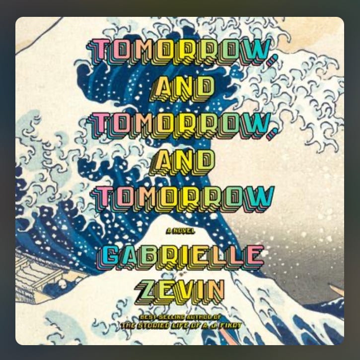 A screengrab of a book cover featuring a looming blue wave with a white surface and a tan boat getting caught at the edge of the wave and a title in rainbow colors reading "Tomorrow, And Tomorrow, And Tomorrow: A novel Gabrielle Zevin Best seller author of 'The Storied Life of A. J. Fikry'" imposed on top.