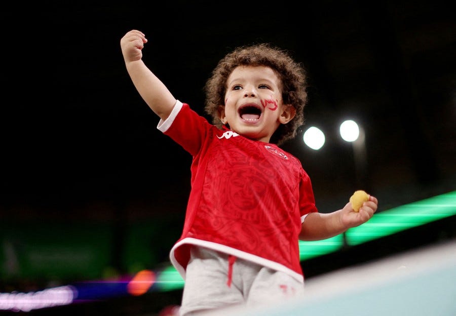 A young soccer fan stands and cheers in a stadium.