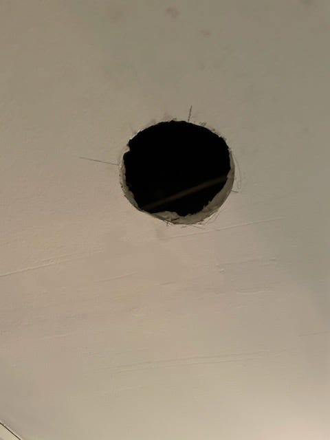 Photo of a 3.5 inch hole in the ceiling drywall of my second-floor hallway, prepped to install a new light. 