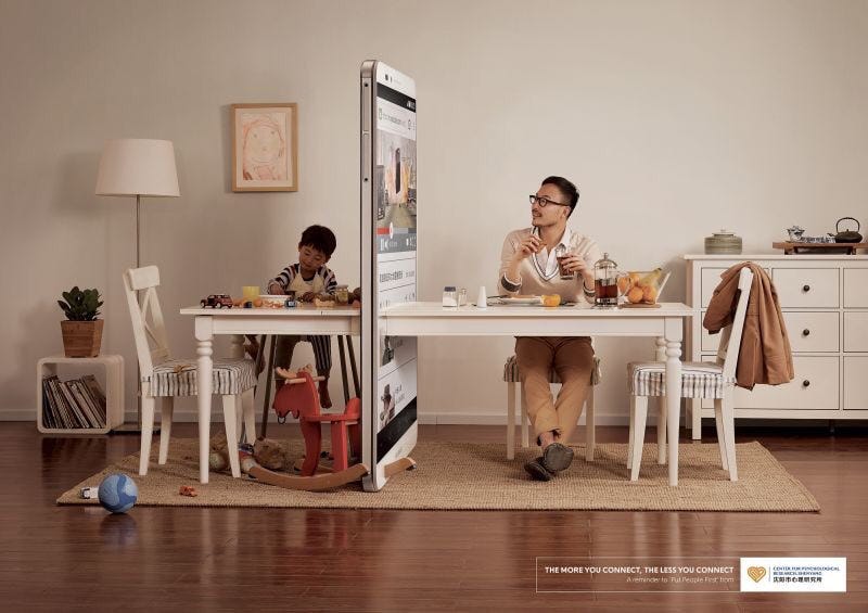 Image of father and son sitting together at the breakfast table. However, the father is looking at his phone which is represented by a large phone dividing the table and putting a wall between him and his son.