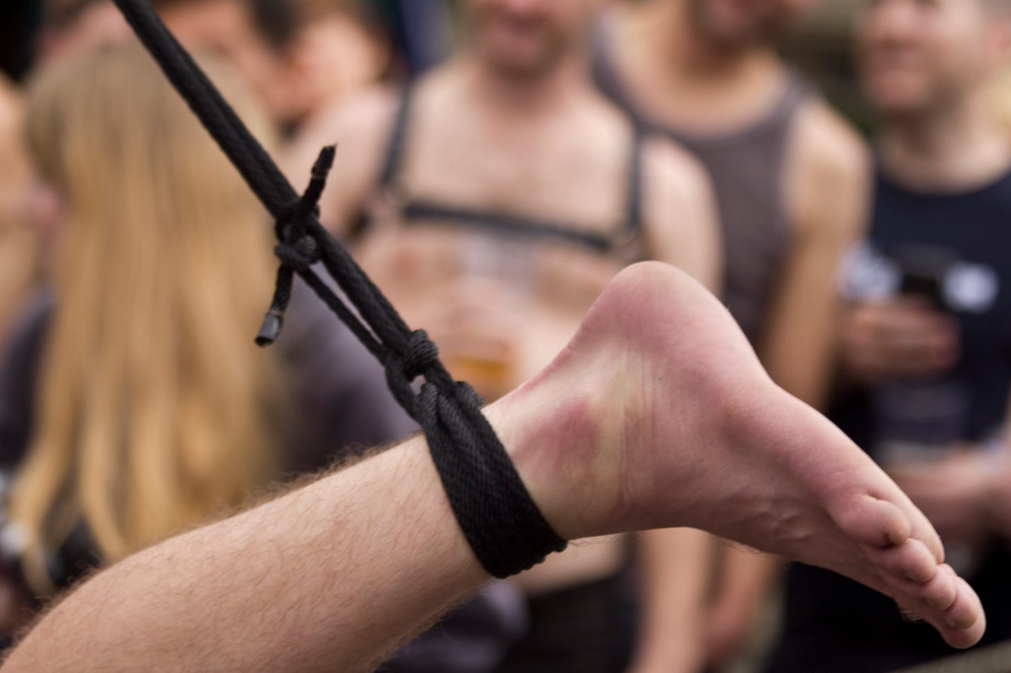 A suspended foot tied up with black rope at a Folsom Street Fair event.