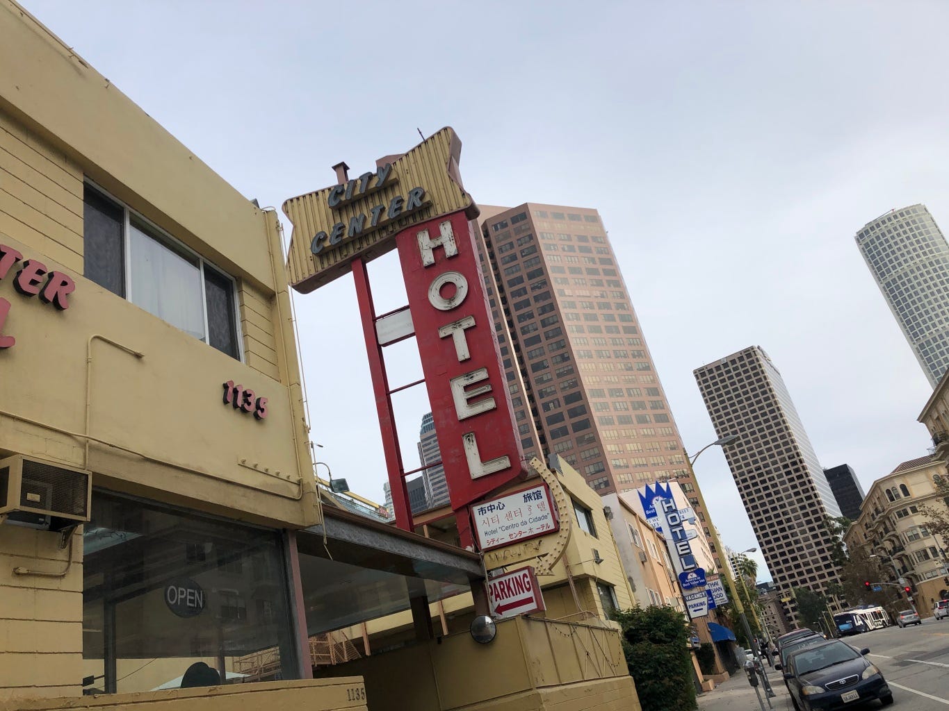 A picture of a vintage hotel sign in Downtown Los Angeles, with skyscrapers in the background.