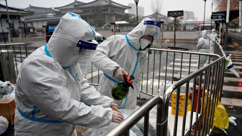 Workers disinfect packed vegetables at a residential area under quarantine in Xi&#39;an, China, on December 25, 2021. 