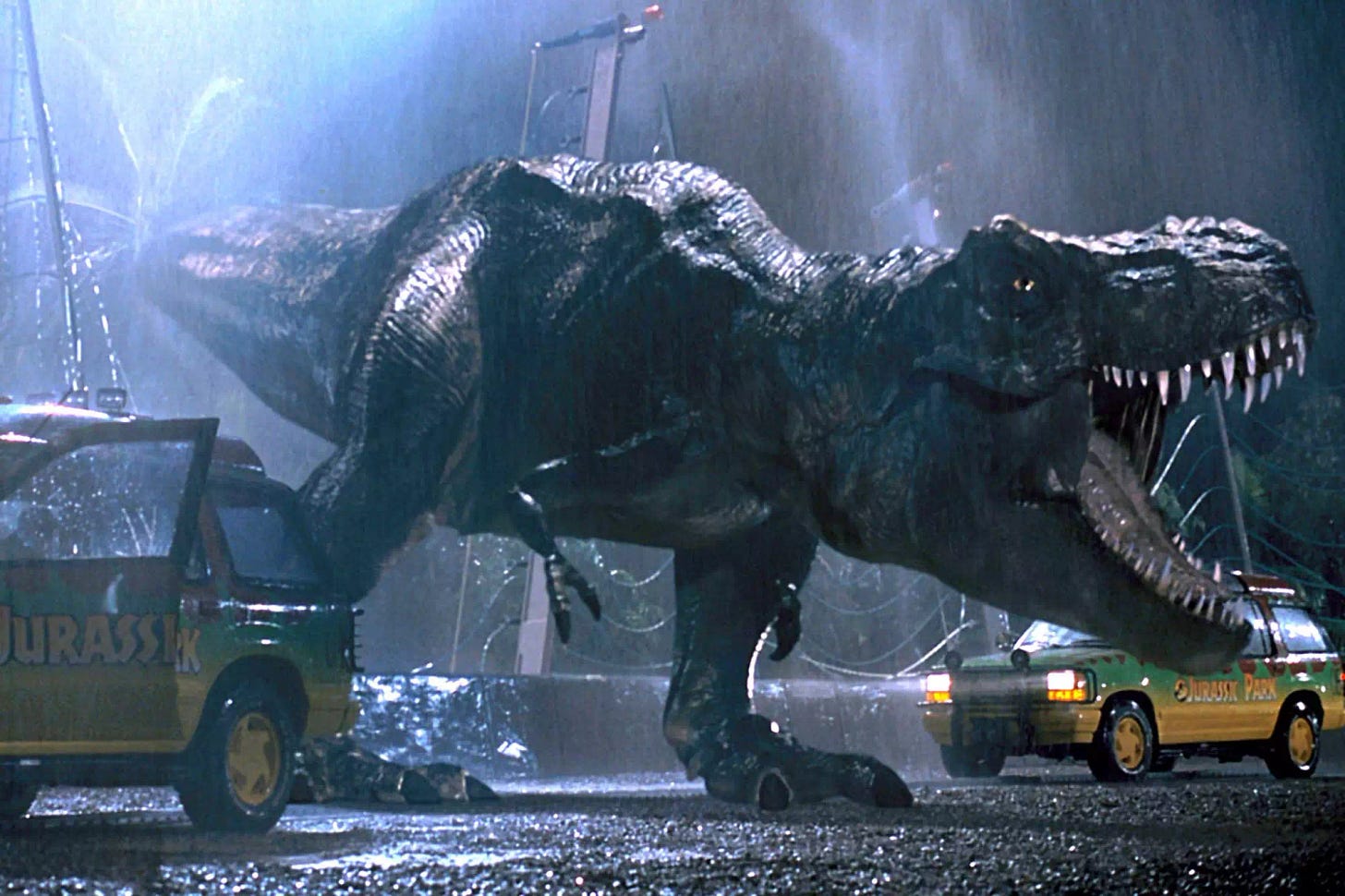 A T-Rex roars between two cars on a rainy night