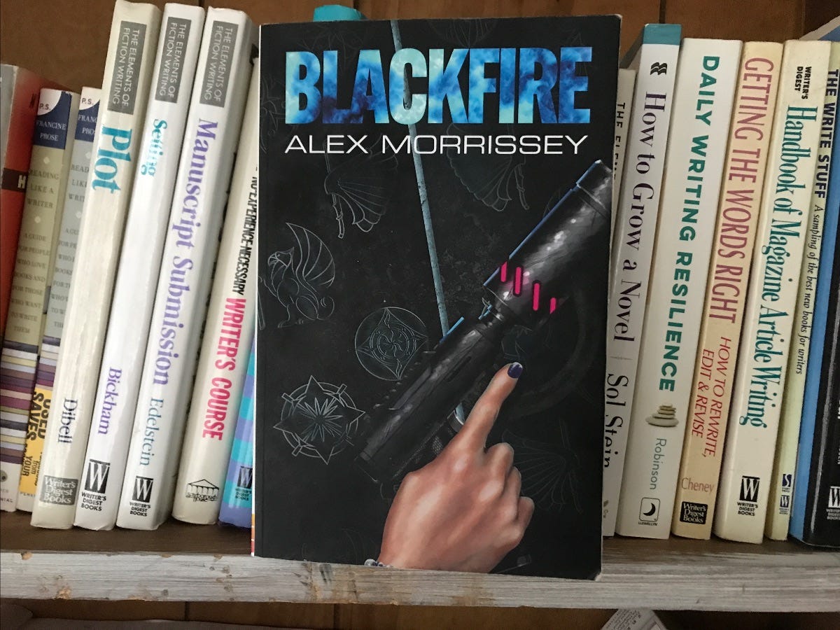 A copy of the novel Blackfire facing out on a shelf of books about writing.