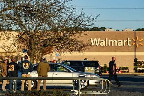 Four law enforcement officers stand in the parking lot outside a Walmart on the day after six employees were killed there.
