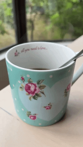 GIF of a beautiful baby-green colour cup with floral patterns, with steam rising up from the hot tea. There’s a cursive-writing sentence on the inner side of the cup with the words, “All you need is love”.