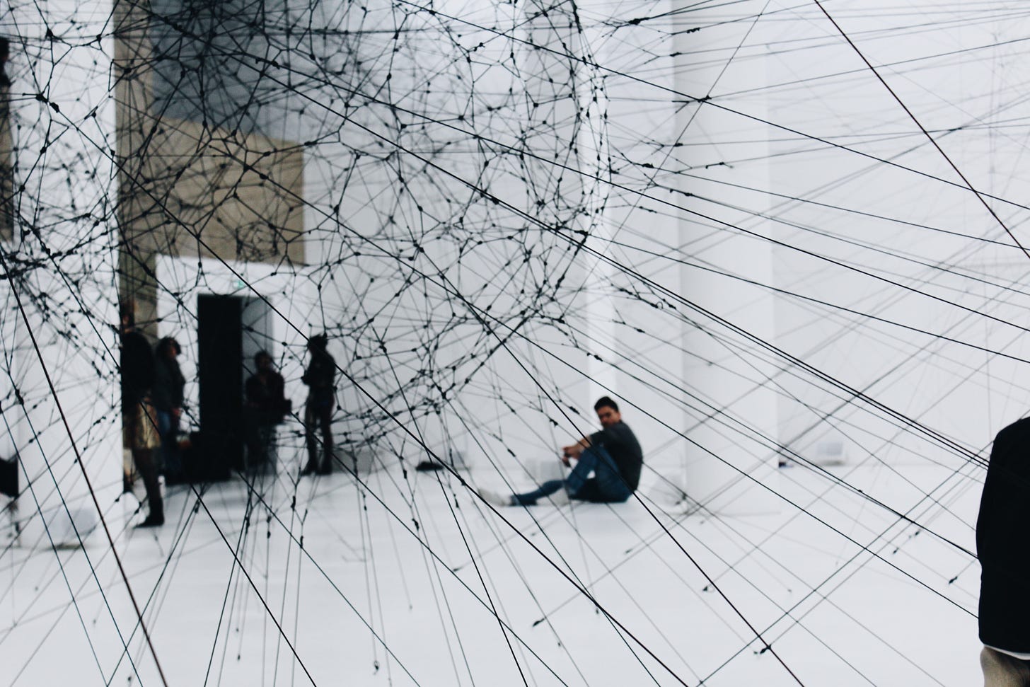 Black clad peoplein a gallery viewed through an abstract geometric black string installation