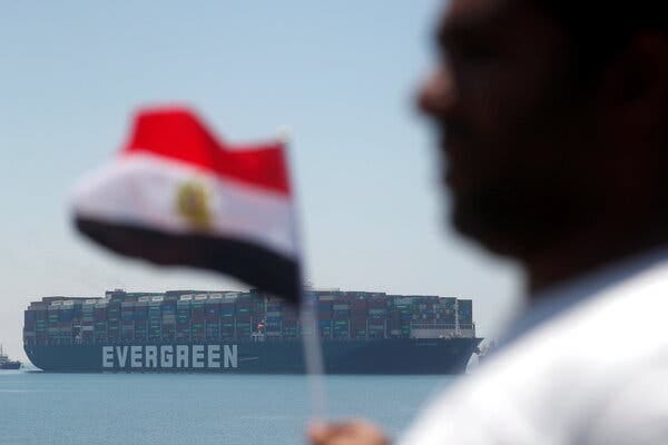 The Ever Given is seen on Wednesday in Egypt. In the foreground, a man with an Egyptian flag.